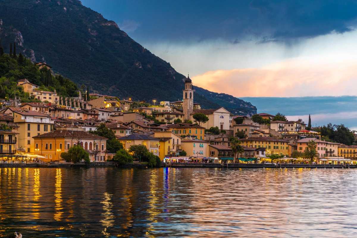 Bambini che giocano in un parco giochi moderno a Limone sul Garda, sfondo lago e limonaia, atmosfera solare e famigliare